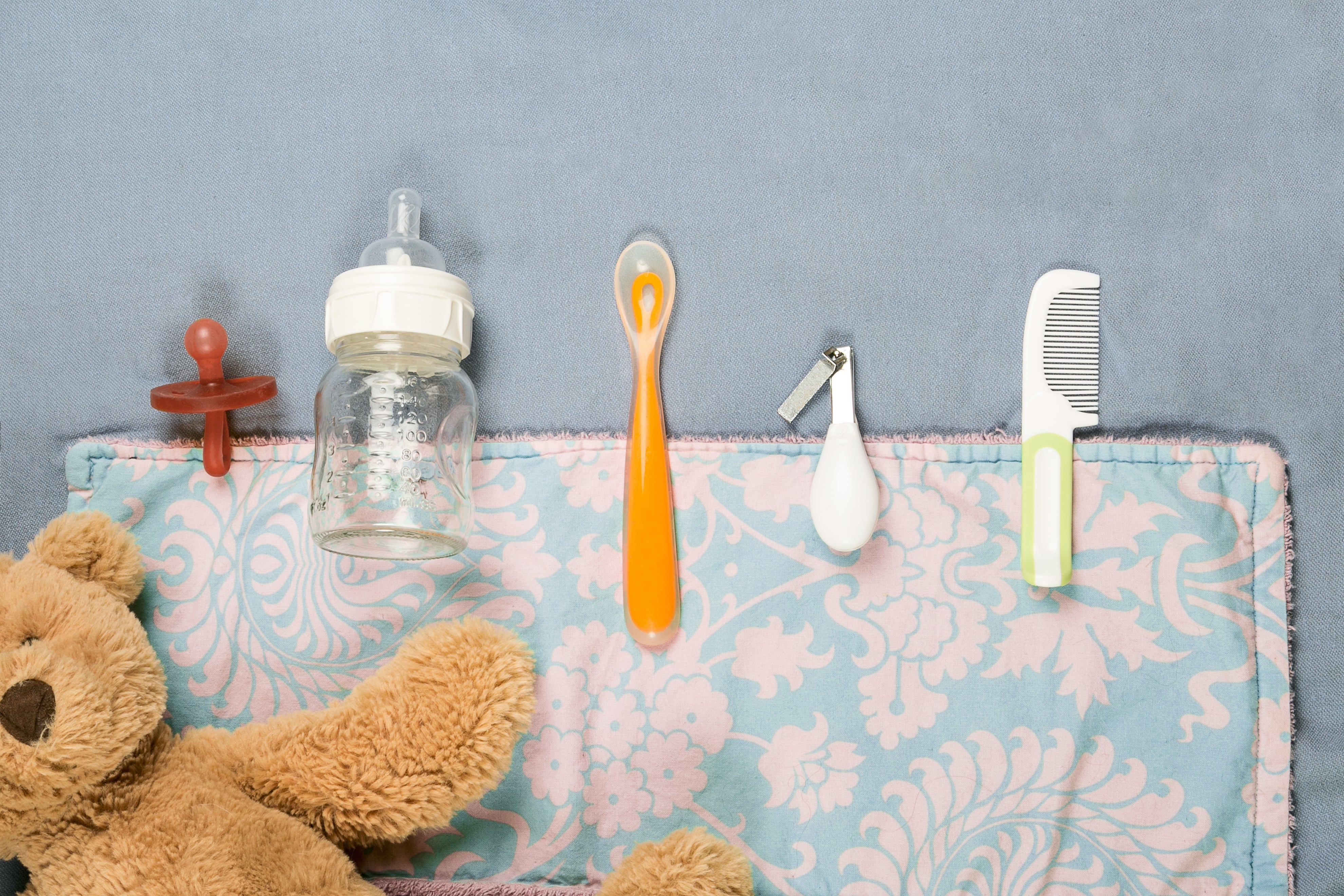 Charming Baby Accessories for Every Little One ✨🍼 - baby bottle, pacifier, spoon, nail clipper, comb on a patterned mat.